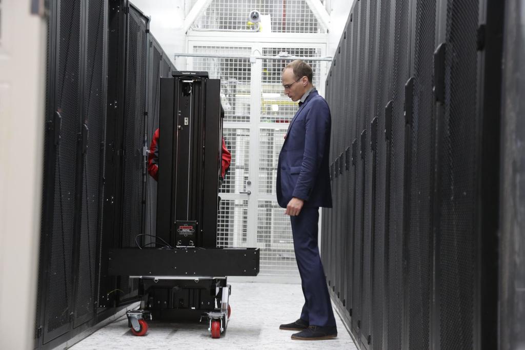 одинокий майнер с ноутбуком на фоне серверных стоек